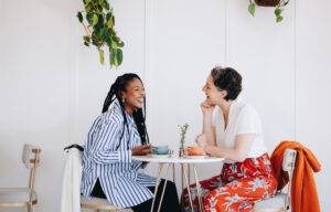 Two happy businesswomen chatting during a coffee break in a cafe - WorldTone