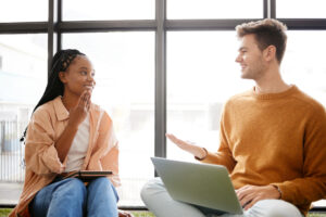 Friends, diversity and student friends talking and speaking together with technology. University students in a discussion chatting about education and study work with a smile happy about working - WorldTone