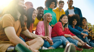 Multicultural group of friends having fun outdoors - Young people celebrate together outside - Soft focus on Asian girl face - WorldTone